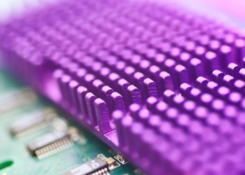 Close-up of a purple-tinted heatsink with pin fins over a green circuit board