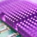 Close-up of a purple-tinted heatsink with pin fins over a green circuit board