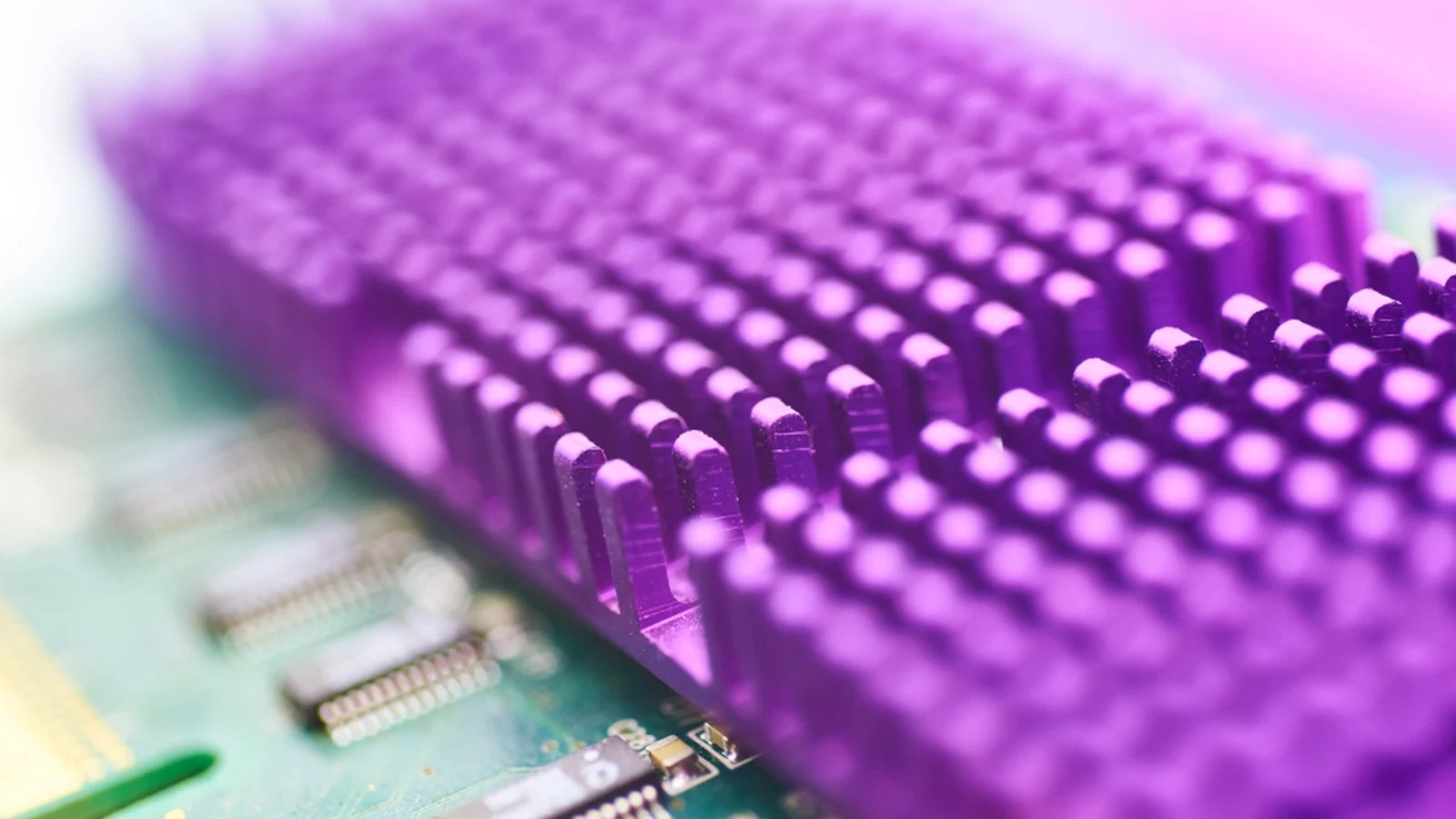 Close-up of a purple-tinted heatsink with pin fins over a green circuit board