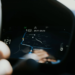 Blurred hand near a car instrument cluster showing a navigation map with a blue route line