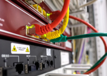 Close-up of a network switch with red, yellow, and green ethernet cables plugged into ports