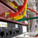 Close-up of a network switch with red, yellow, and green ethernet cables plugged into ports