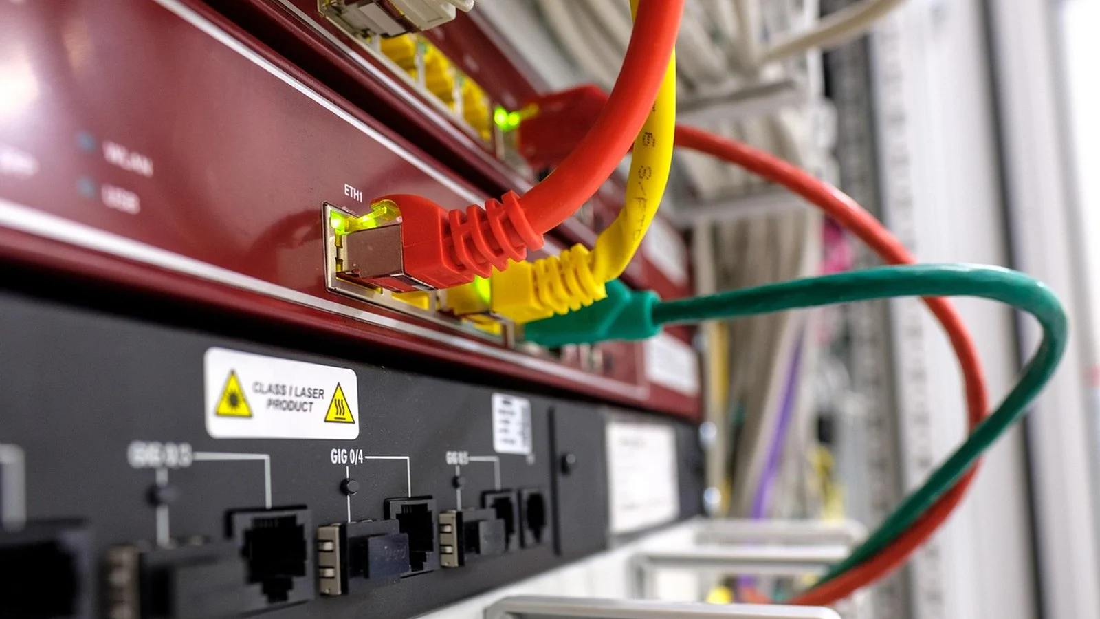 Close-up of a network switch with red, yellow, and green ethernet cables plugged into ports