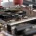 A hand lowers a silver processor chip into an empty socket on a motherboard