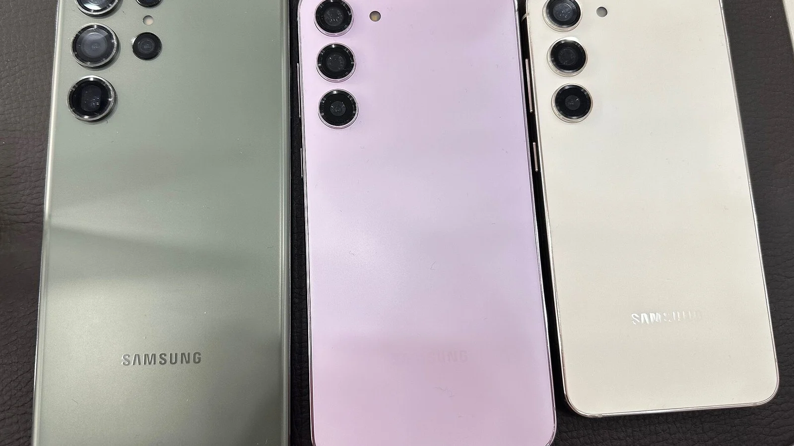 Three Samsung phone backs side by side, green with many cameras, purple and cream with three cameras