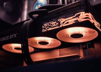 GeForce RTX graphics card installed in a PC case, three fans lit orange under RGB lighting