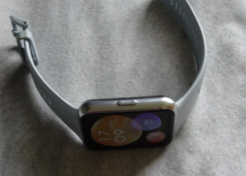 Gray silicone smartwatch with blurry colorful screen on a wrinkled fabric surface
