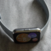 Gray silicone smartwatch with blurry colorful screen on a wrinkled fabric surface