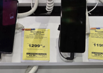 Two Motorola smartphones on security cables at a store display next to yellow Polish price tags