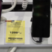 Two Motorola smartphones on security cables at a store display next to yellow Polish price tags
