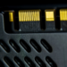 Extreme close-up of gold connector pins on a black perforated heat spreader