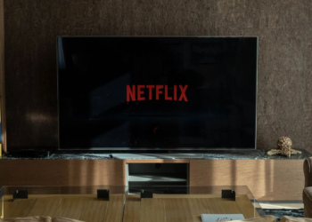 A flat-screen TV in a living room showing the red Netflix logo on a black loading screen