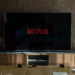 A flat-screen TV in a living room showing the red Netflix logo on a black loading screen