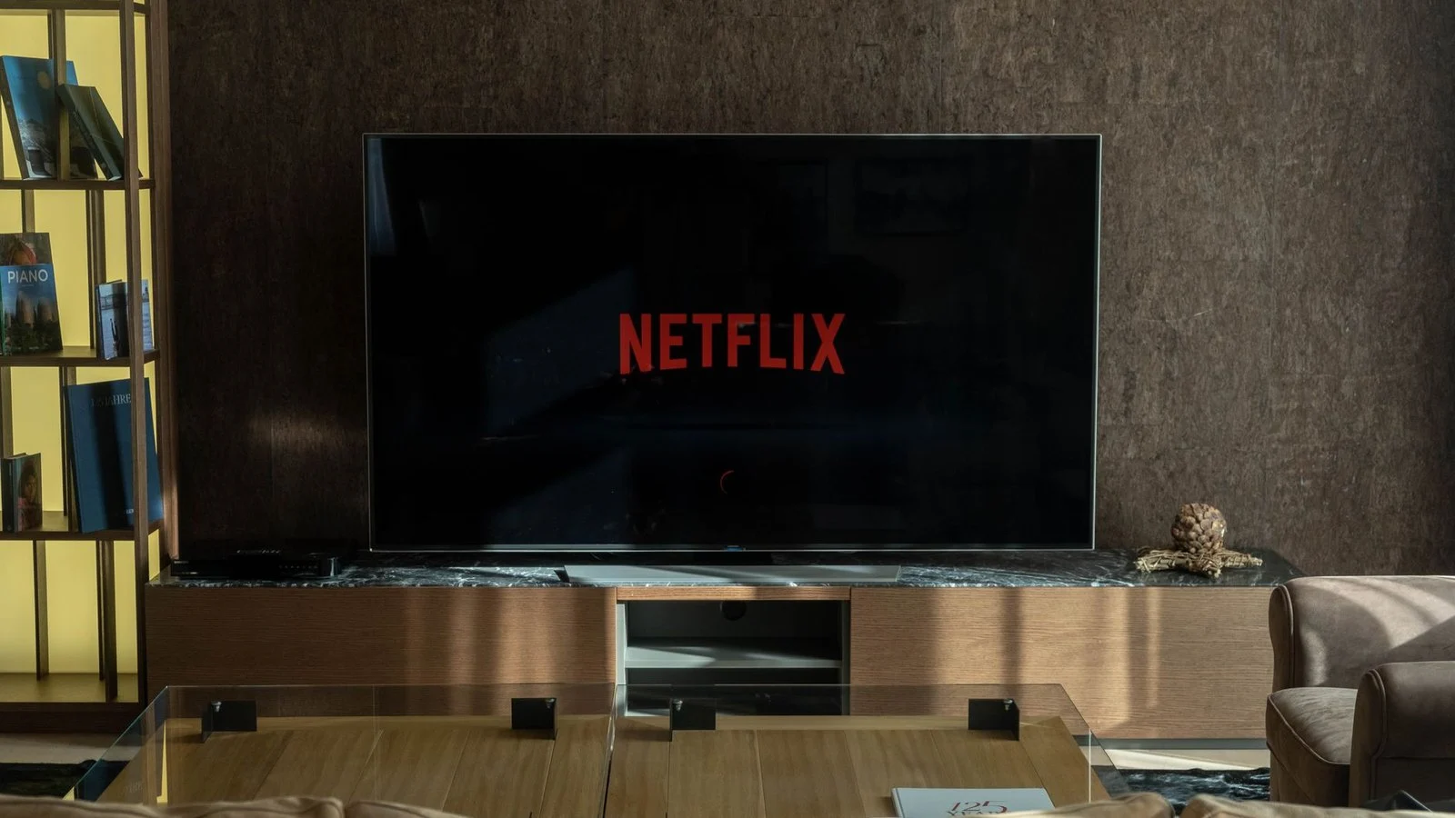 A flat-screen TV in a living room showing the red Netflix logo on a black loading screen