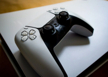 A white DualSense controller resting on top of a white PlayStation 5 console
