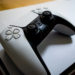 A white DualSense controller resting on top of a white PlayStation 5 console