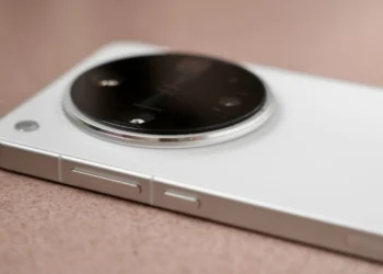Close-up of a white smartphone's large round camera bump with multiple lenses on a tan surface