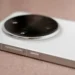 Close-up of a white smartphone's large round camera bump with multiple lenses on a tan surface