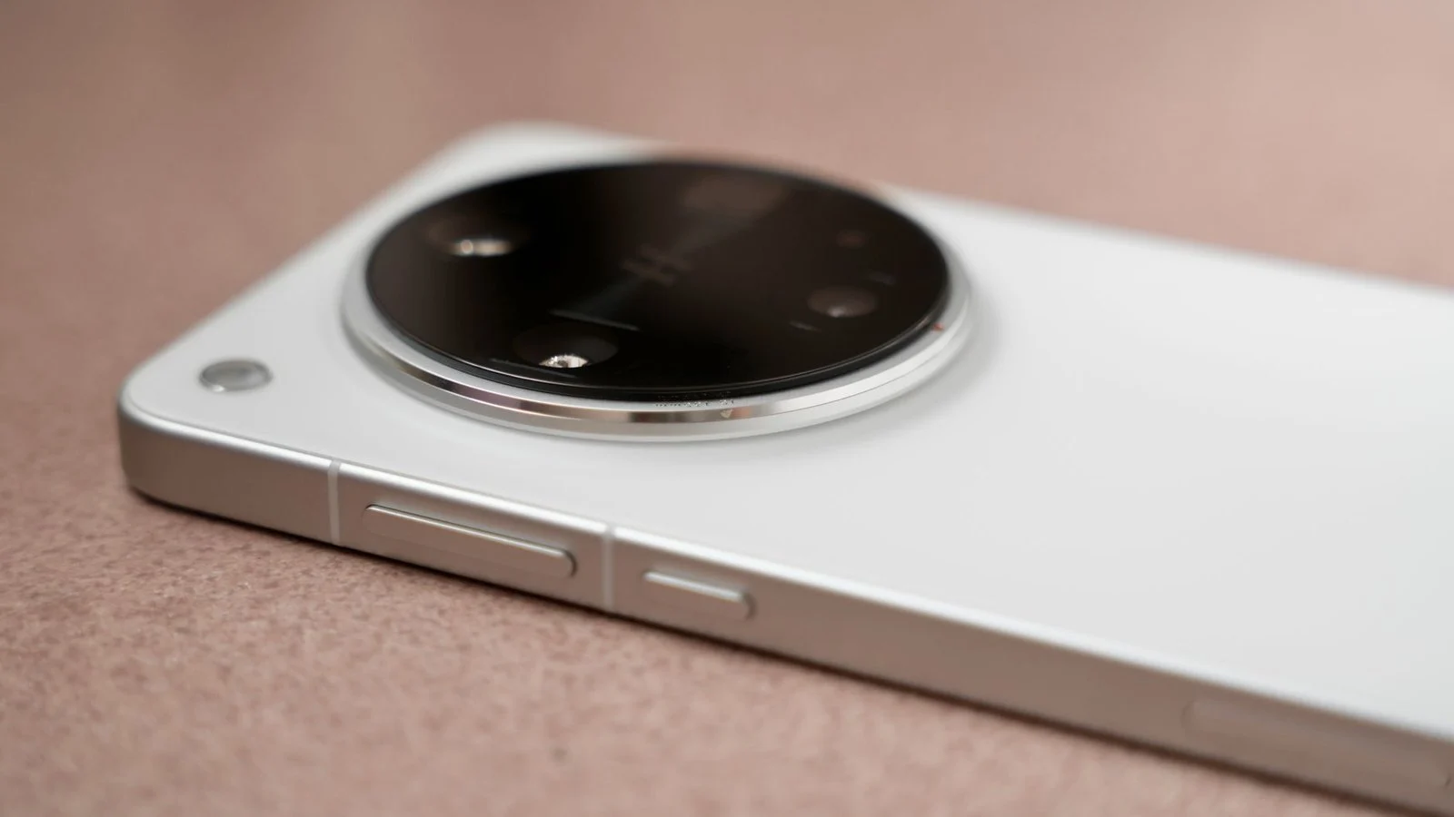 Close-up of a white smartphone's large round camera bump with multiple lenses on a tan surface