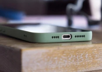 close-up of a phone's bottom edge in a green case showing USB-C port on a wooden table