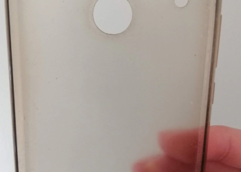 Blurry close-up of a translucent phone case with a white circular ring, held by a hand