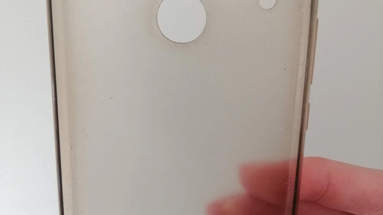 Blurry close-up of a translucent phone case with a white circular ring, held by a hand