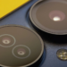 Macro shot of a dark smartphone's circular rear camera lenses and flash on a yellow background