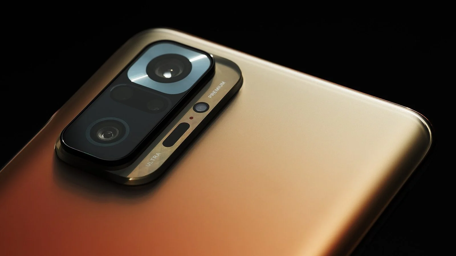 Close-up of a gold smartphone's rear camera module with three round lenses and PREMIUM/ULTRA text