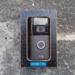 A Ring video doorbell with camera and glowing blue button mounted on a stone wall
