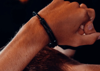 Close-up of a person's wrists bound behind their back in steel handcuffs