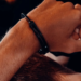 Close-up of a person's wrists bound behind their back in steel handcuffs