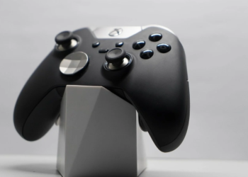 Black and silver Xbox Elite controller resting on a white geometric display stand