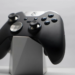 Black and silver Xbox Elite controller resting on a white geometric display stand