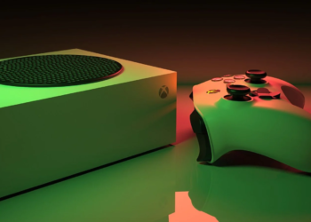 Green-lit rectangular game console and matching controller on a reflective surface