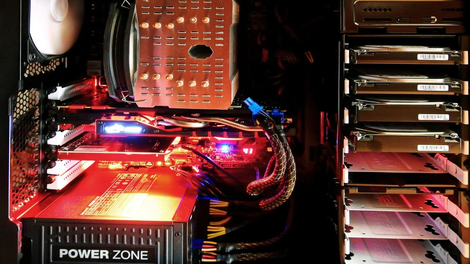 Interior of a red-lit PC case showing a PSU labeled Power Zone and drive bays