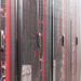 Row of server racks with mesh doors and red and blue cables visible inside