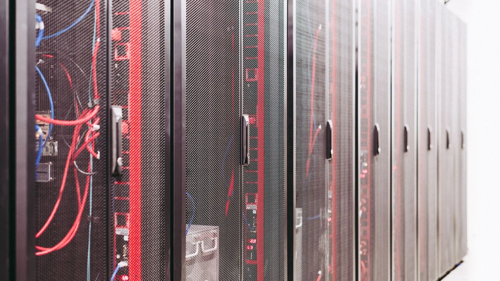 Row of server racks with mesh doors and red and blue cables visible inside