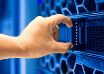 A hand adjusts a component in a blue-lit server rack