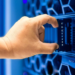 A hand adjusts a component in a blue-lit server rack
