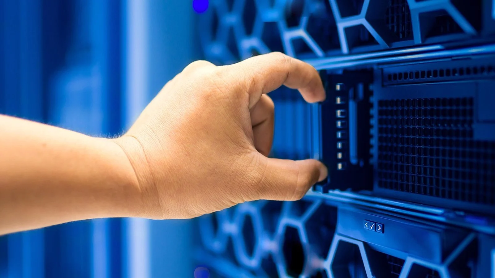 A hand adjusts a component in a blue-lit server rack