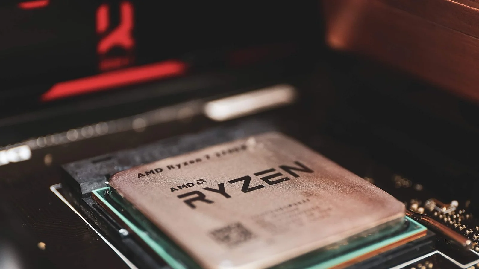 AMD Ryzen processor seated in its motherboard socket, close-up with red RGB lighting in background