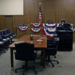 Empty wood-paneled courtroom with patriotic bunting, American flag, and jury chairs