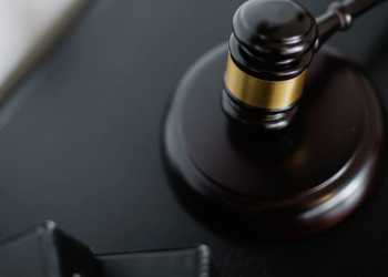 Wooden gavel resting on its sound block on a dark table