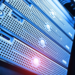 Close-up of a generic silver rack-mounted server chassis with perforated panels under blue and red lighting