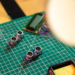 Ultrasonic sensor modules and a small LCD on a green cutting mat near a soldering iron