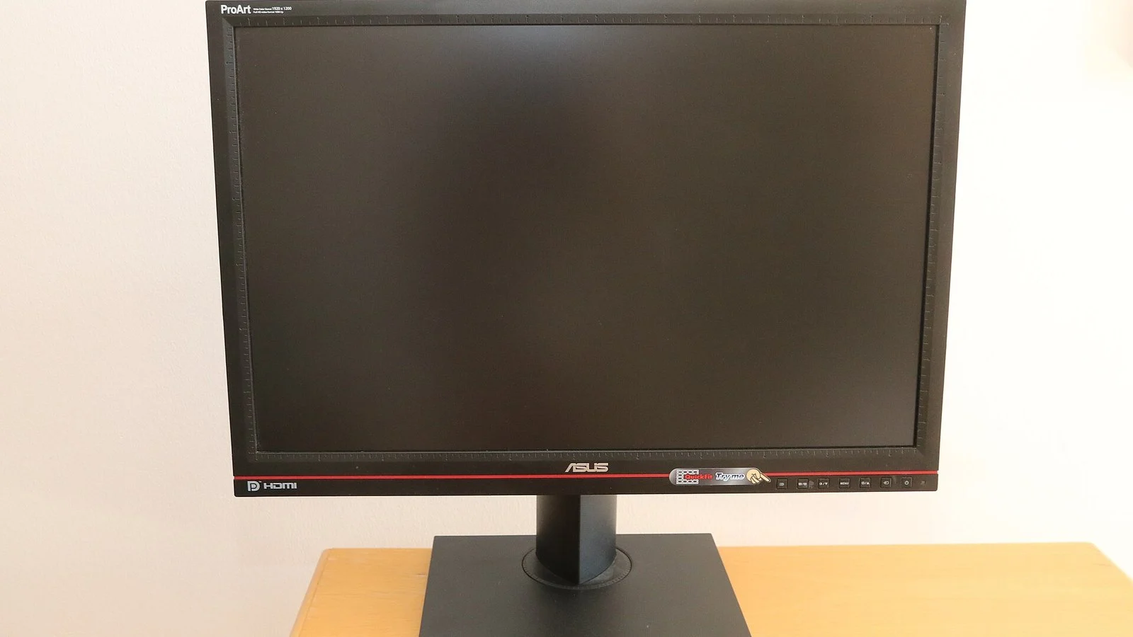 ASUS ProArt monitor with black screen off, on a stand, against a white wall