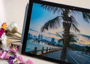 Surface tablet on a table showing a Windows Hello lock screen, beside dried flowers and candy