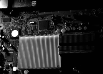 Close-up of a dark circuit board with a large finned heatsink, desaturated high-contrast photo