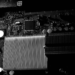 Close-up of a dark circuit board with a large finned heatsink, desaturated high-contrast photo