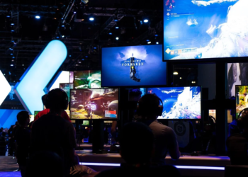 Convention attendees at gaming demo stations under screens reading 'Destiny 2 Forsaken.'